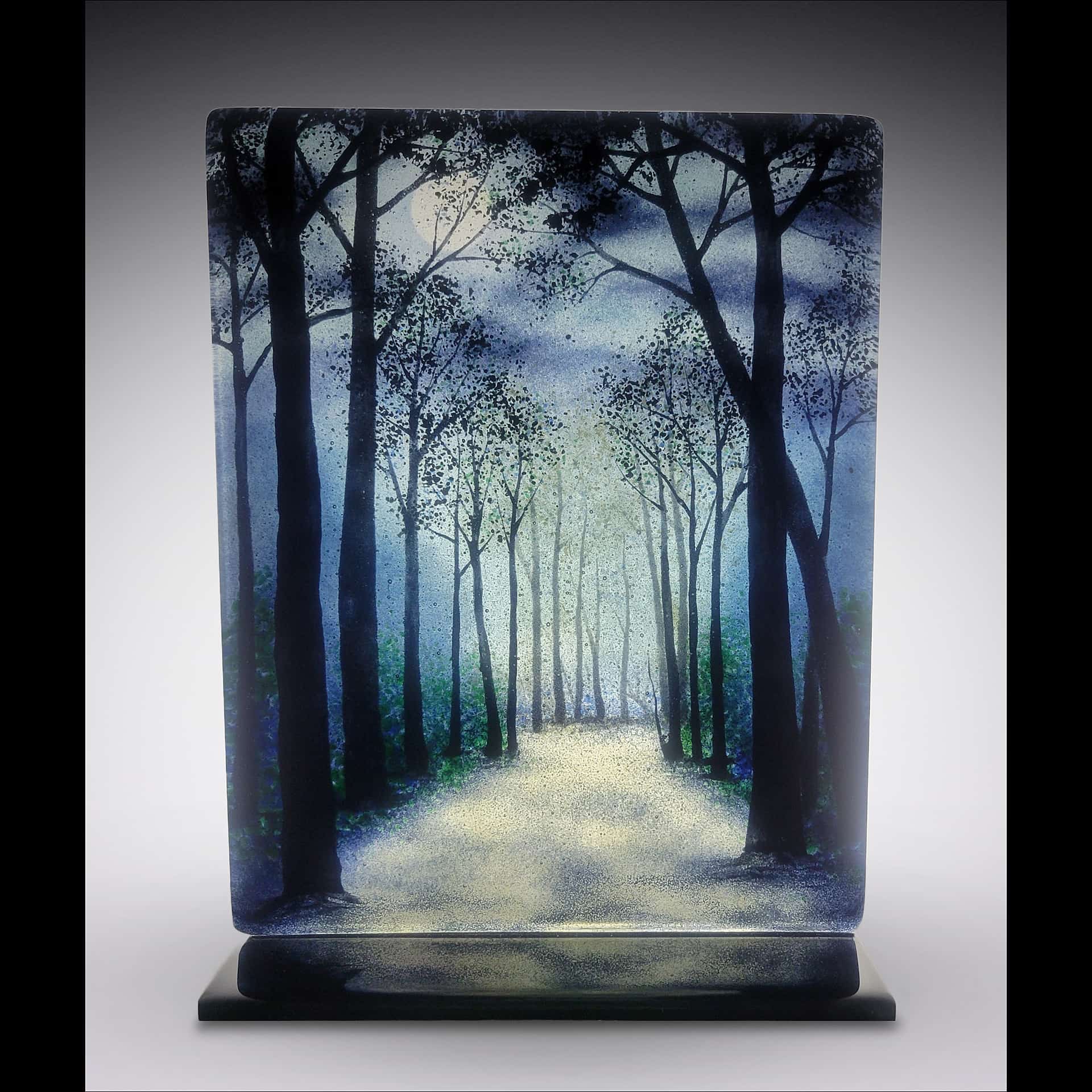 Fused-glass artwork by David Norton depicting a moonlit forest path in cool blues and soft whites, created with Bullseye clear sheet, colored frit, and Rogue black enamel, fired in a Jen-Ken Profusion 26 kiln.